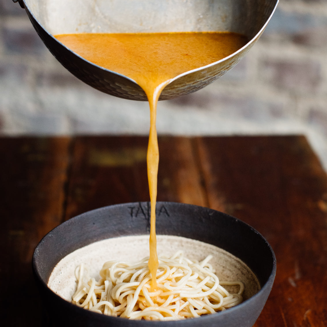 Erwärmte TADA Ramenbrühe in einer Schüssel, serviert mit Nudeln und Toppings